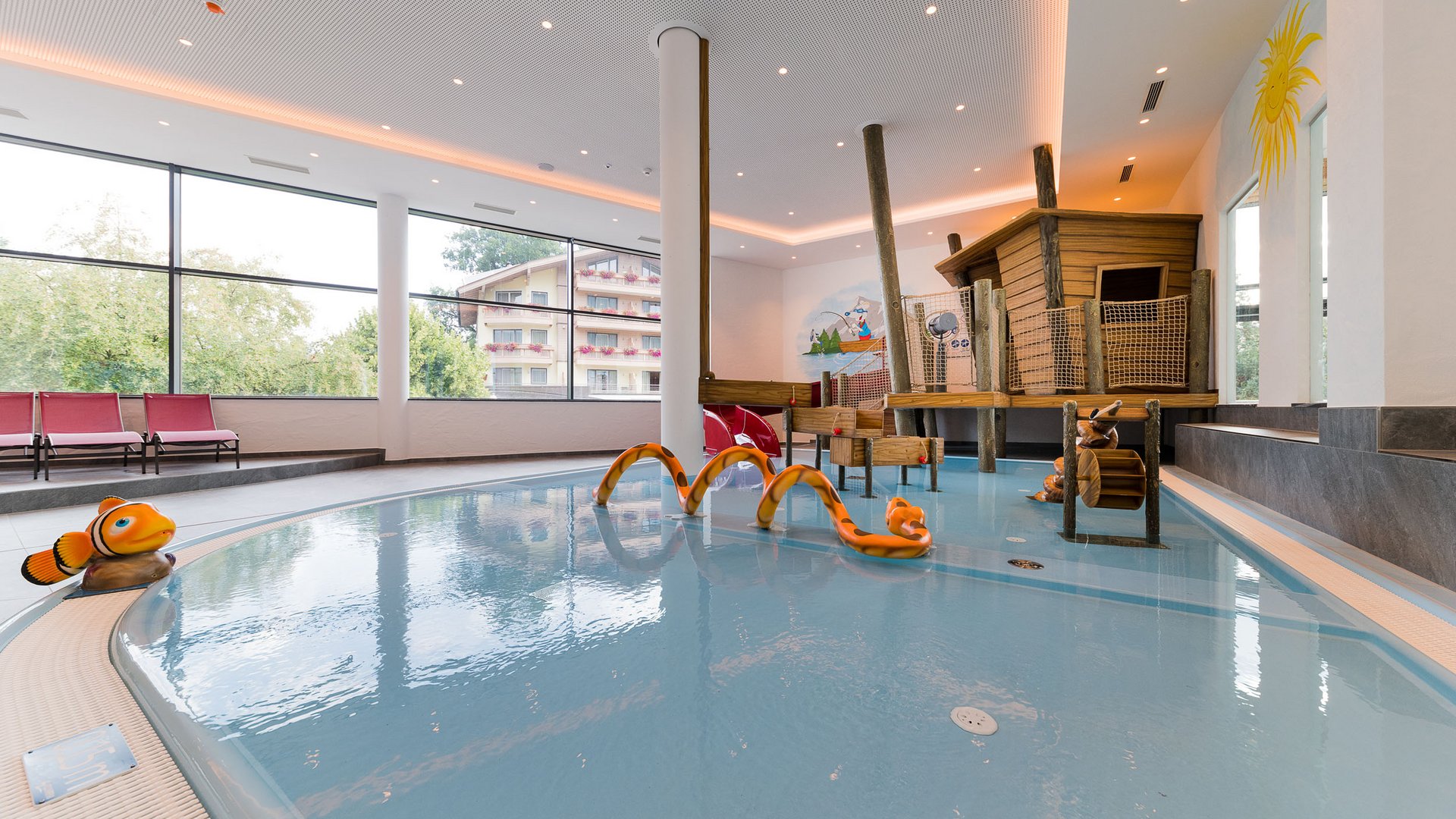 Hallenbad für Kinder mit bunten Wasserspielelementen und Holzspielhaus (© Hotel Woferlgut - Klaus Bauer)