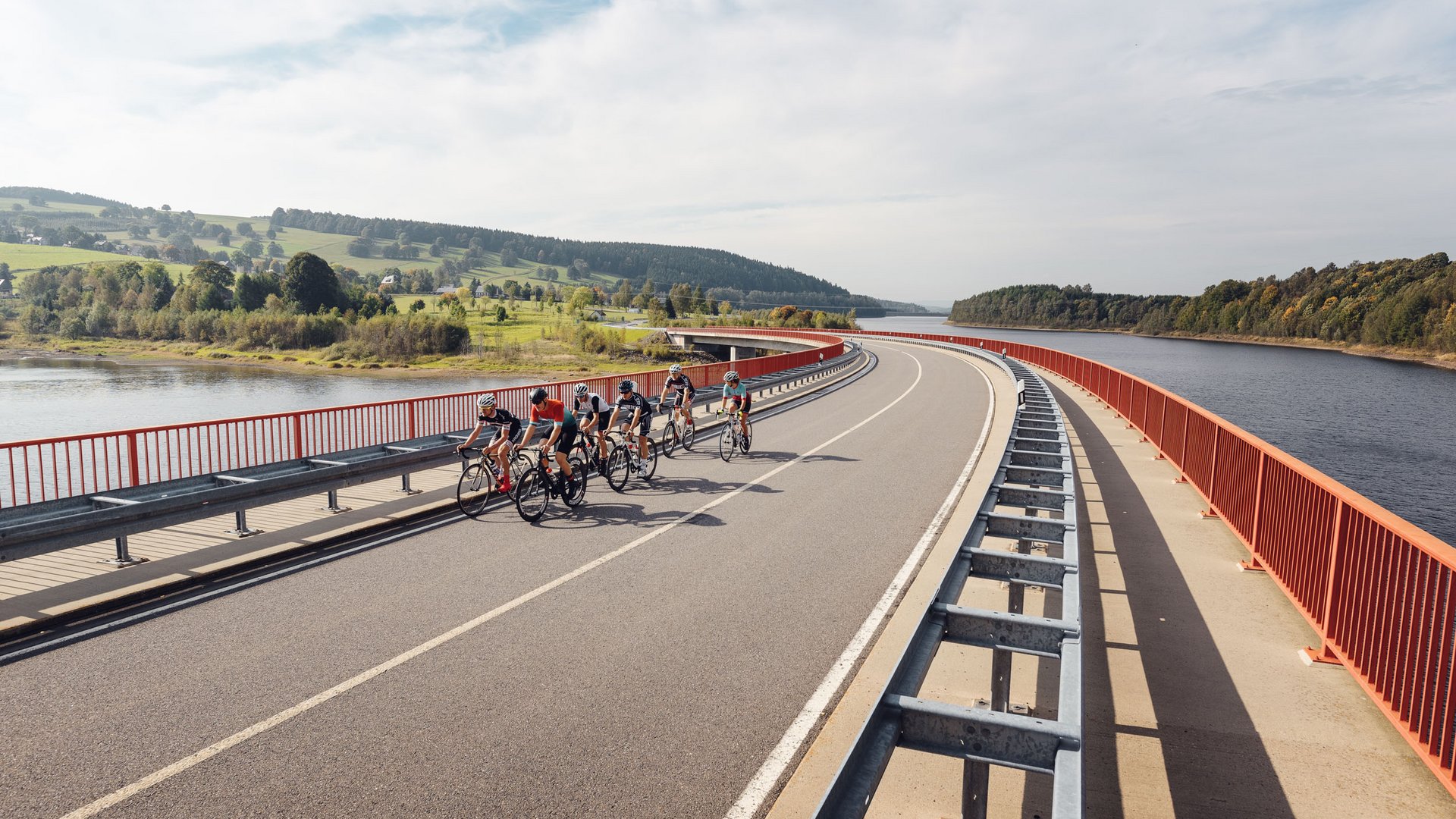 Radfahrer auf einer Brücke über einem Stausee mit grünen Hügeln (© Erzgebirge - Felix Meyer)